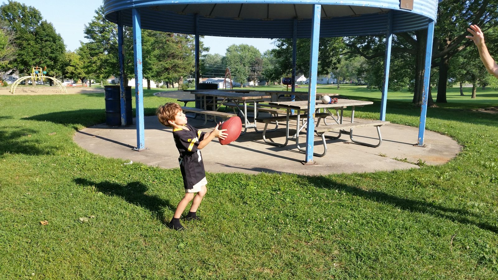 Thomas throws a football under the park pavilion