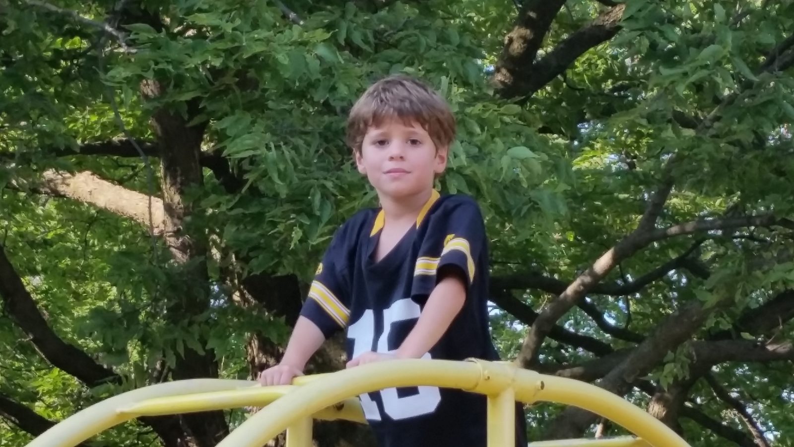 Thomas climbs the playground's arch climbers