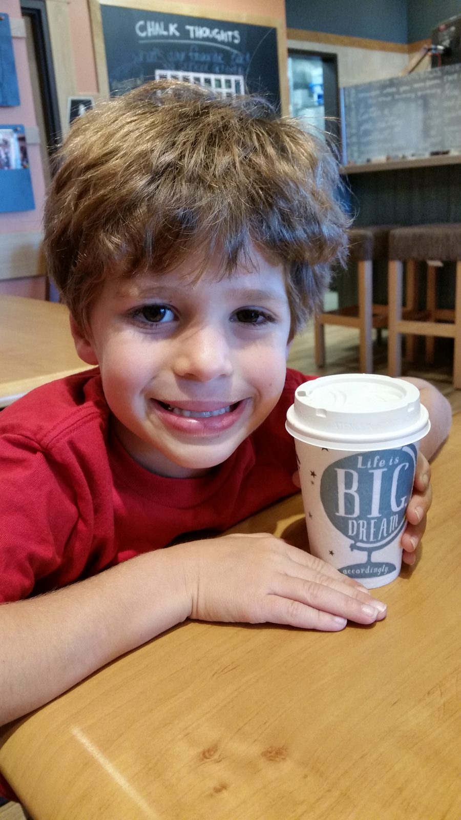 Thomas smiles with his coffee cup