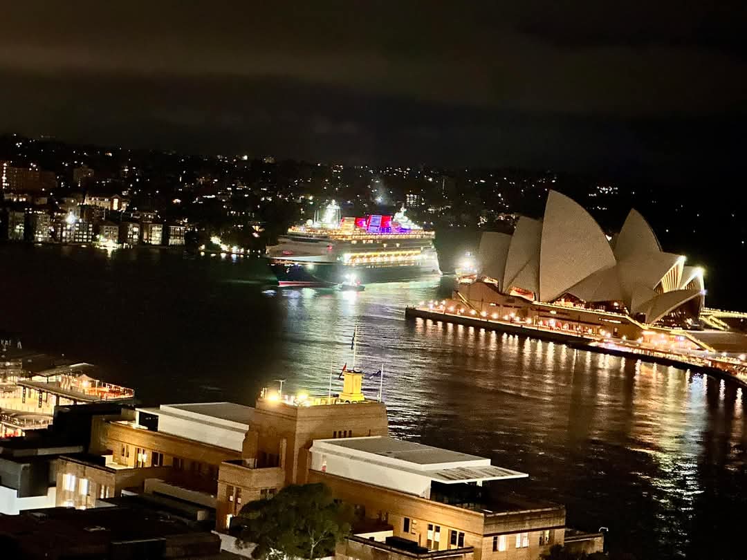 Sydney Harbour lit up at night, a ship at the quay
