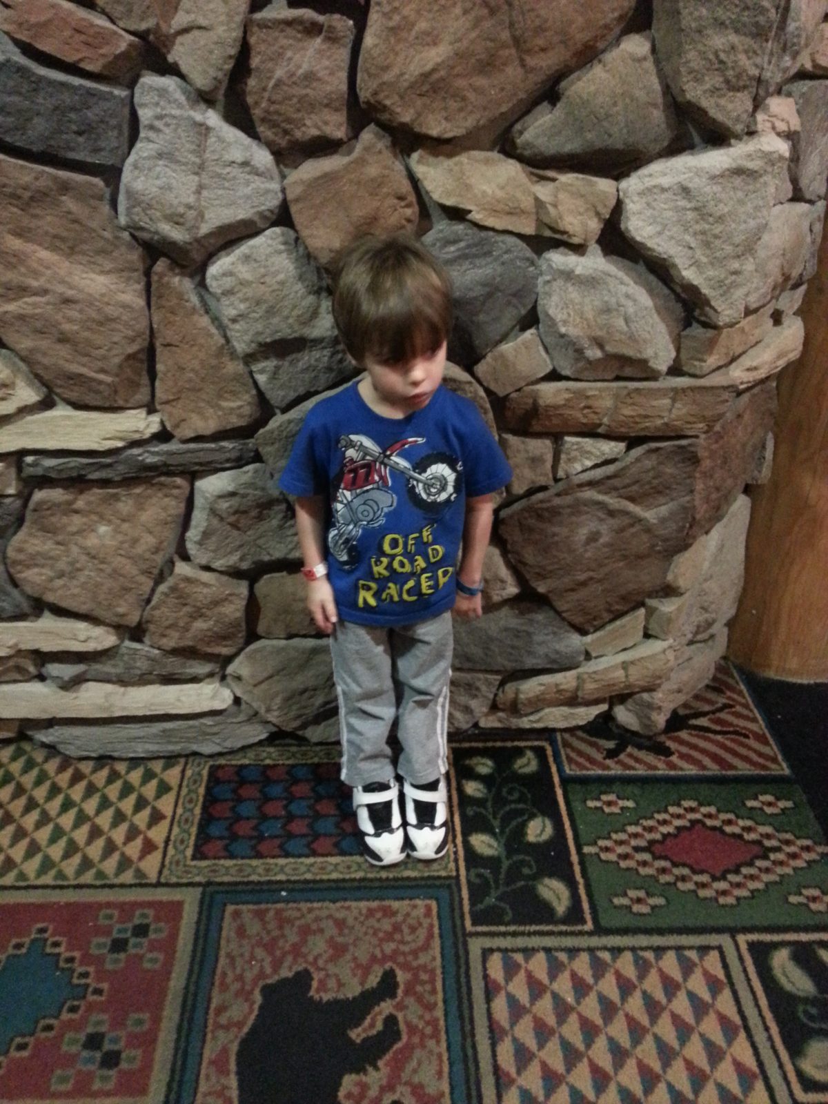 Thomas dwarfed by the lodge's stone wall